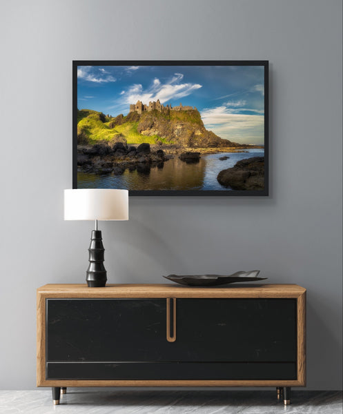 Framed wall art print of Dunluce Castle perched on rugged cliffs in Northern Ireland. The medieval ruins, set against a dramatic coastal backdrop, capture the castle's historic and scenic beauty. Perfect for adding a touch of elegance and history to any room.