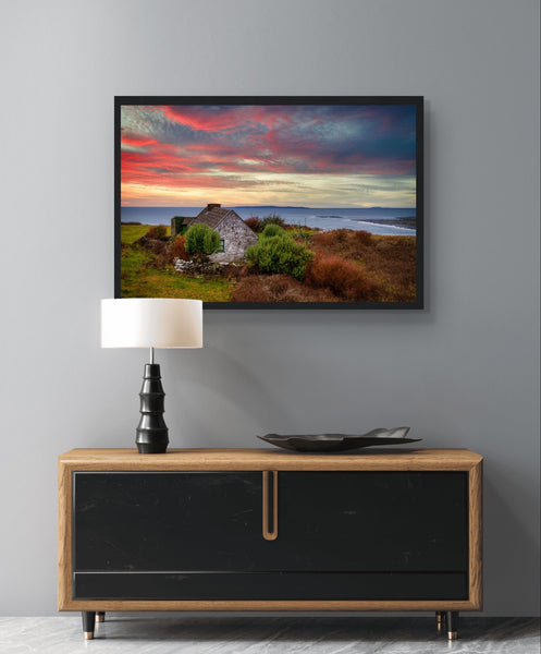 Art print: Serene sunset over Atlantic Ocean, Doolin, Co. Clare, Ireland. Small cottage nestled amid coastal cliffs, vibrant sky in hues of orange and pink, capturing tranquil beauty of Irish countryside.