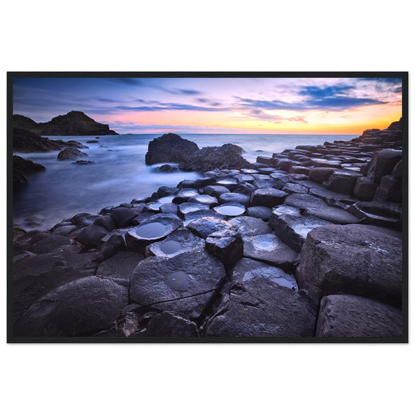 Framed art print of a breathtaking sunset at Giant's Causeway. Features iconic basalt columns against a warm, colorful sky. Perfect for adding sophistication and natural beauty to any home or office decor. Ideal for nature and art enthusiasts.