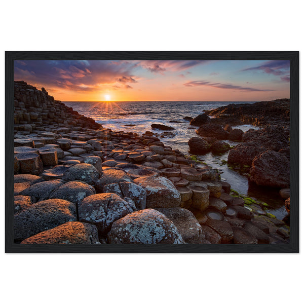 Framed art print of a mesmerizing sunset at Giant's Causeway, featuring iconic basalt columns under a sky painted with warm hues. Captures nature's beauty and tranquility, adding a sophisticated touch to any home or office decor. Ideal for art enthusiasts.