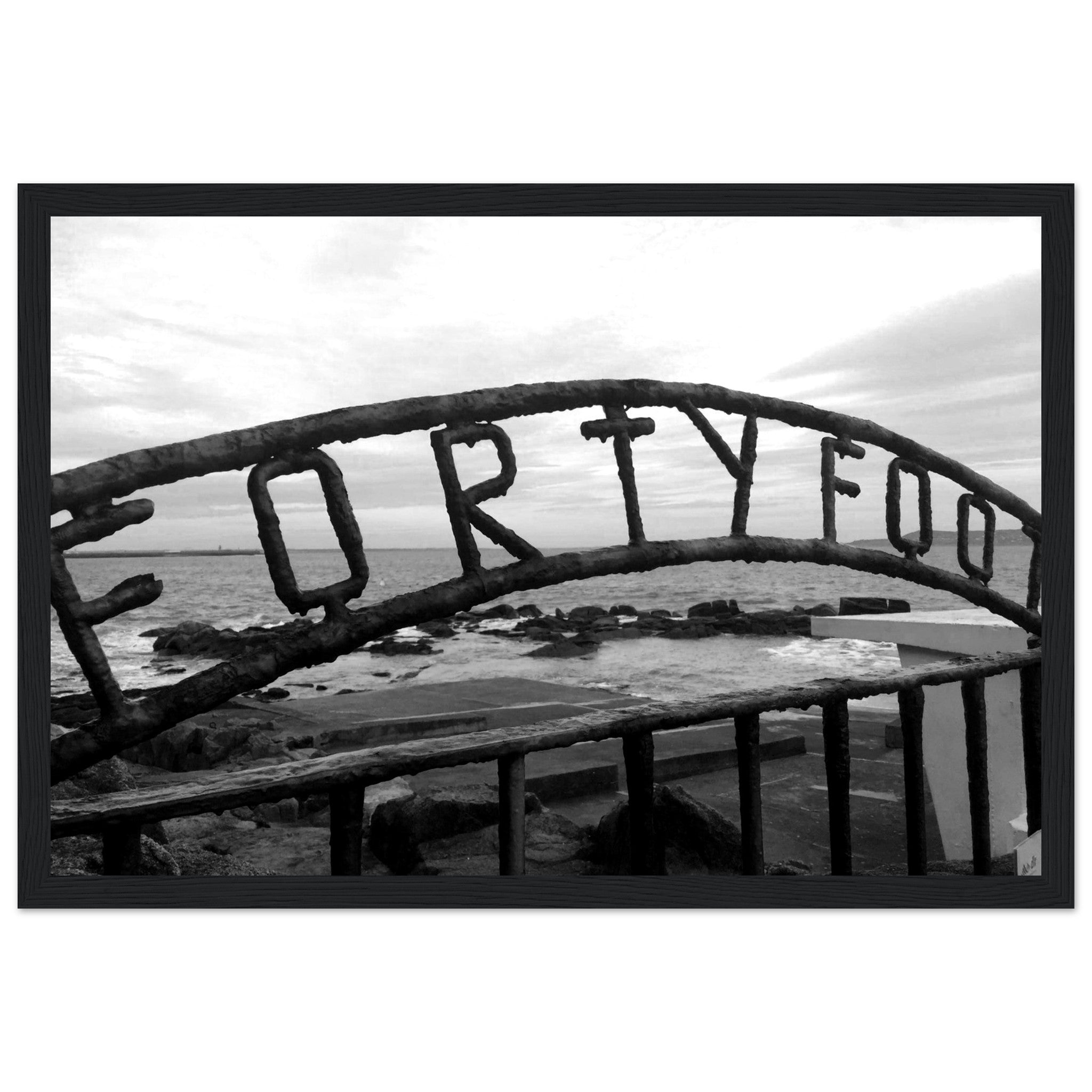 Monochrome seascape photo capturing the serene beauty of the Forty Foot bathing spot in Dublin, Ireland. Martello tower stands in the distance against a clear sky.